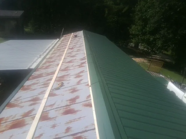 Old rusted panels beside newly installed green metal roofing — Wind Damage Roof Repair by Roofing Brothers in Wattsburg