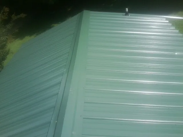 New green metal panels meeting at the ridge of a roof — Flat Roof Repair work by our crew in Wattsburg