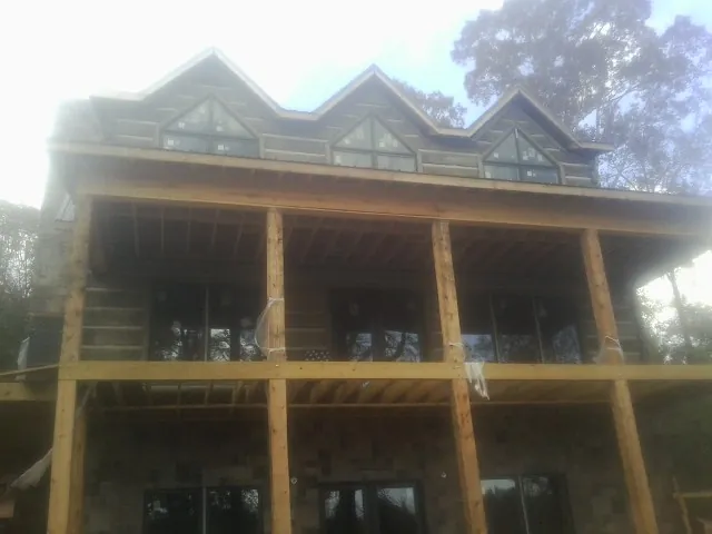 Dormers and porch framing on a large log home under construction — Roof Coating work by our crew in Wattsburg