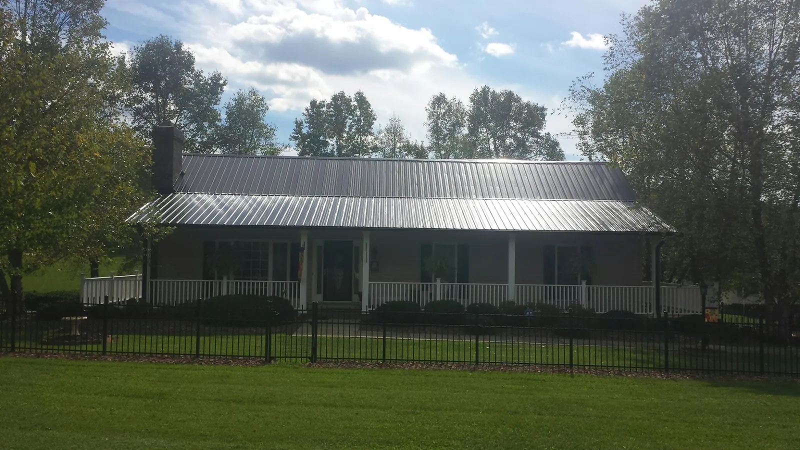 Gray metal roof on a brick ranch with a full width front porch — Gutter Guard Installation work by our crew in Wattsburg